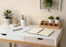 A desk with a notebook, pen, and a plant photo