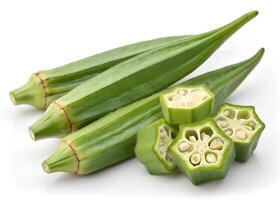 Fresh okra pods and slices are displayed on a white surface photo