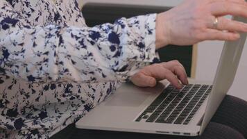 Extreme closeup of elderly womans hands while she types on laptop computer keyboard. video