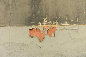 Peeling paint reveals layers of history on a weathered wall in an old urban setting photo