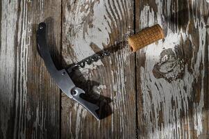 Corkscrew and cork resting on rustic wooden table in warm sunlight, a moment before the gathering begins photo