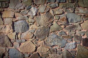 Textured stone wall showcasing natural hues and shapes from centuries of craftsmanship in a rustic setting photo