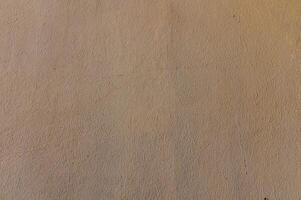 Texture of a sunlit wall offering a warm canvas of earthy tones and subtle variations in shadows photo
