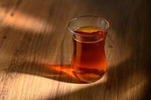 Delightful amber tea resting gracefully on a wooden table illuminated by soft afternoon light photo