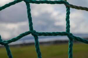 Vivid turquoise netting frames a blurred landscape under an expansive cloudy sky in a serene outdoor setting photo