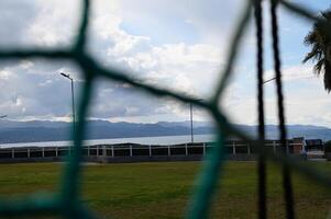 Scenic view through a goal net at a peaceful lakeside park during a cloudy afternoon photo