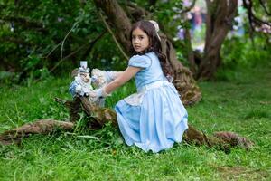 Pretty young girl in blue dress playing in forest with figurine photo