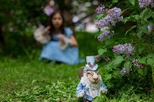 White rabbit figurine in garden with young caucasian girl in background photo