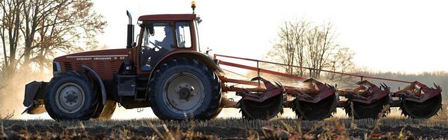 Autumn tractor plowing field at sunset photo