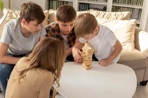 A woman and three boys are enthusiastically playing a board game made of wooden rectangular blocks photo