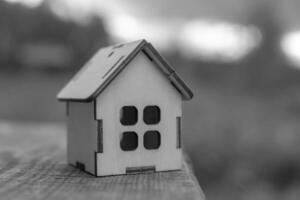 a small wooden toy house stands on the edge of a wooden table, may fall down. photo