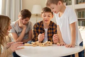 Three boys and a woman in the room are playing a board game made of wooden rectangular blocks photo