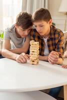 A two teen boys are enthusiastically playing a board game made of wooden rectangular blocks photo