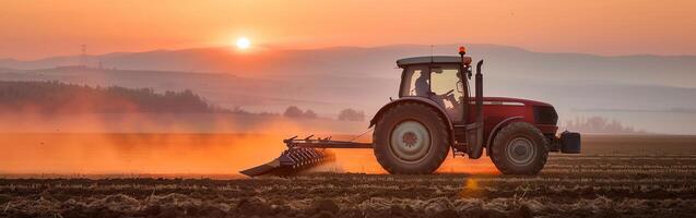 Tractor at sunset on dusty farm field with scenic backdrop photo