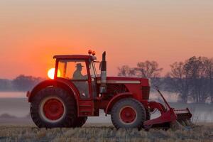 Silhouette of farmer on red tractor at sunset in serene rural landscape photo