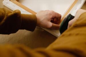 Hands stretching canvas on stretcher bars using staple gun. Gallery wrap. Print on canvas. photo
