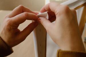 Framer hands bend edges of canvas. Stretching blank canvas on stretcher frame. Close-up. photo