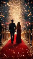 Elegant couple walks hand in hand down a glamorous red carpet at a formal event adorned with sparkling lights photo