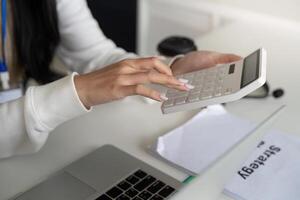 Financial analyst calculating tax refund and deductions using a calculator at a desk. photo