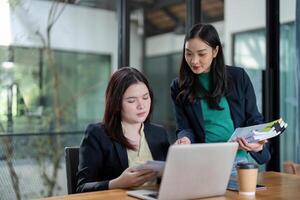Team members engaged in financial planning and analysis with documents and a laptop in a collaborative space. photo