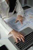 Accountant analyzing financial data on a laptop while reviewing tax documents. photo