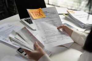 Person analyzing tax paperwork and using a calculator for financial calculations. photo