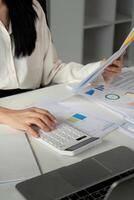 Accountant using a calculator and reviewing financial reports in a modern workspace. photo