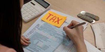 Woman calculating taxes with forms and calculator, showcasing financial management skills. photo