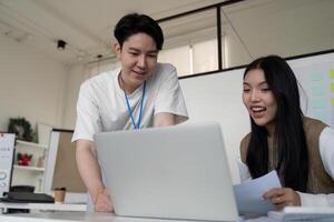 Young professionals collaborating on financial analysis using a laptop in a modern office setting. photo