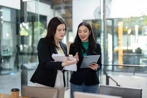 Business partners collaborating on a project with documents and a tablet in a modern office setting. photo