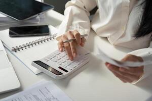 Calculating financial data with a calculator while reviewing receipts and notes for tax preparation. photo
