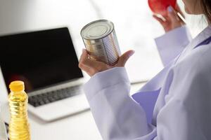 Nutrition and analysis. Nutritionist comparing food choices with a can and a fresh apple. photo