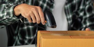 Close-up of a young man scanning a package with a barcode scanner in a workspace. photo