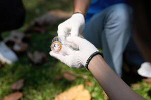 Focused volunteer examining a plastic bottle during a community cleanup event. photo