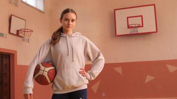 Young female basketball player posing in a gym with ball and hoop video