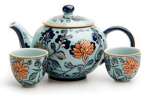 Light blue ceramic teapot with two matching cups decorated with orange flowers and dark blue leaves photo