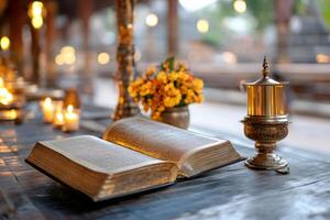Open bible lying on wooden table with candles and flowers in buddhist temple photo
