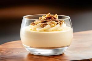 Creamy dessert with walnuts and pecan nuts in a glass bowl on wooden table photo