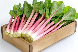 Fresh rhubarb stalks with leaves resting in wooden crate photo