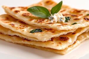 Stack of golden flatbreads garnished with fresh basil and cheese photo