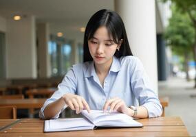 Asian woman studying at table in outdoor cafe photo