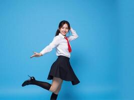 A young woman in a school uniform is jumping and dancing photo