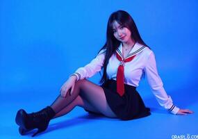A woman in a school uniform sitting on a blue background photo