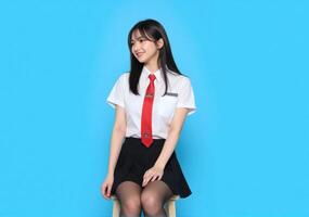 A young woman in a school uniform sitting on a stool photo