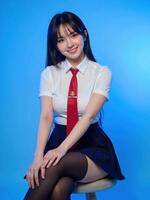 A woman in a school uniform sitting on a stool photo
