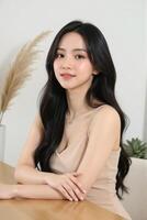 An asian woman sitting at a table with her arms crossed photo
