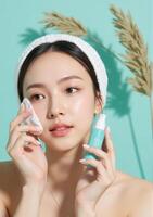 A woman with a towel on her head and a bottle of skin care product photo
