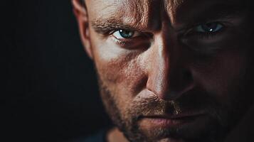 Intense gaze of a man in the shadows His brow is furrowed and his eyes are piercing His gaze emanates strength and intensity photo