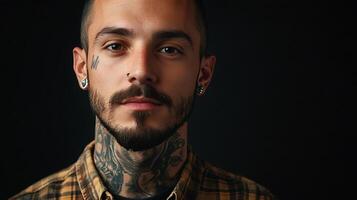 Intense portrait of a man with tattoos piercings and a stylish beard The dark backdrop intensifies the focus on his distinct features photo