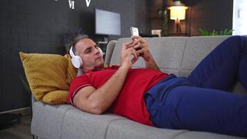 Relaxing at home while enjoying music and scrolling through a smartphone at dusk video